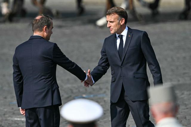 France's President Emmanuel Macron (R) shakes hands with France's Prime Minister Sebastien Lecornu (L) during the annual Bastille Day military parade on the Champs-Elysees Avenue in Paris on July 14, 2026. (Photo by LOU BENOIST / AFP)