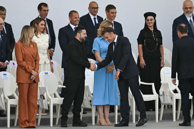 France's President Emmanuel Macron (C-R) shakes hands with Ukraine's President Volodymyr Zelensky (C-L) on the Place de la Concorde during the annual Bastille Day military parade in Paris on July 14, 2026. (Photo by LOU BENOIST / AFP)