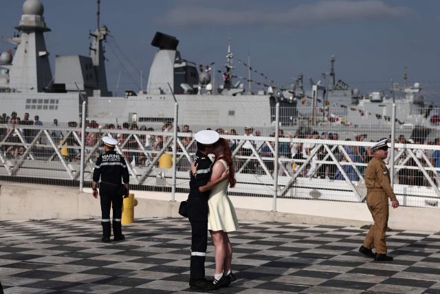 A member of the French Navy kisses a relative as he disembarks from the amphibious helicopter carrier (PHA) 'Dixmude' upon its arrival in the port of Toulon, south-eastern France on July 14, 2026, as the "Jeanne d’Arc" task force concludes a five-month mission. Nearly 800 service members took part in this deployment, including 162 officer cadets. This annual deployment marks the culmination of the training of French and foreign officer cadets at the Naval Academy. (Photo by Thibaud MORITZ / AFP)
