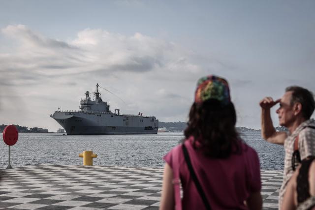 Relatives and spectators wait for the arrival of the amphibious helicopter carrier (PHA) 'Dixmude' in the port of Toulon, south-eastern France on July 14, 2026, as the "Jeanne d’Arc" task force concludes a five-month mission. Nearly 800 service members took part in this deployment, including 162 officer cadets. This annual deployment marks the culmination of the training of French and foreign officer cadets at the Naval Academy. (Photo by Thibaud MORITZ / AFP)