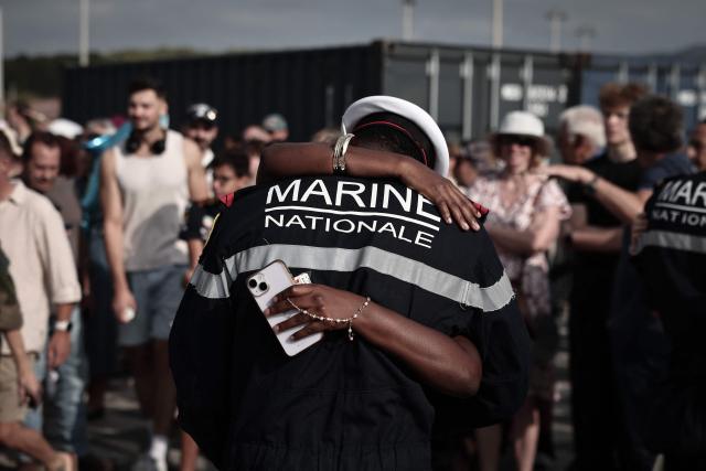 A member of the French Navy greets a relative as he disembarks from the amphibious helicopter carrier (PHA) 'Dixmude' upon its arrival in the port of Toulon, south-eastern France on July 14, 2026, as the "Jeanne d’Arc" task force concludes a five-month mission. Nearly 800 service members took part in this deployment, including 162 officer cadets. This annual deployment marks the culmination of the training of French and foreign officer cadets at the Naval Academy. (Photo by Thibaud MORITZ / AFP)