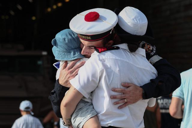 A member of the French Navy greets relatives as he disembarks from the amphibious helicopter carrier (PHA) 'Dixmude' upon its arrival in the port of Toulon, south-eastern France on July 14, 2026, as the "Jeanne d’Arc" task force concludes a five-month mission. Nearly 800 service members took part in this deployment, including 162 officer cadets. This annual deployment marks the culmination of the training of French and foreign officer cadets at the Naval Academy. (Photo by Thibaud MORITZ / AFP)