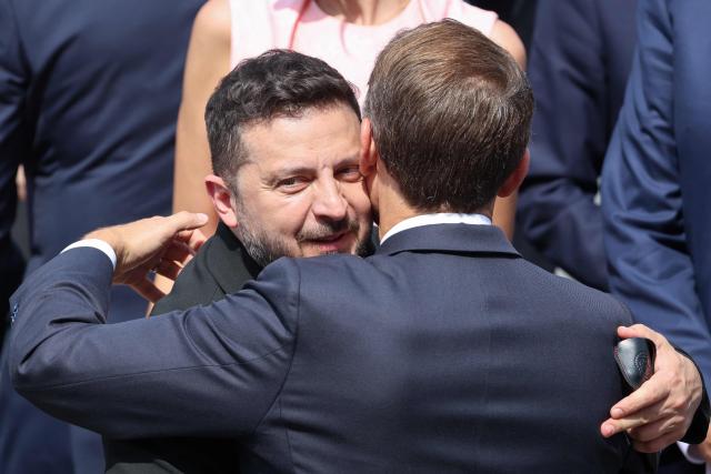 France's President Emmanuel Macron (R) greets Ukraine's President Volodymyr Zelensky during the annual Bastille Day military parade on the Champs-Elysees Avenue in Paris on July 14, 2026. (Photo by Ludovic MARIN / AFP)
