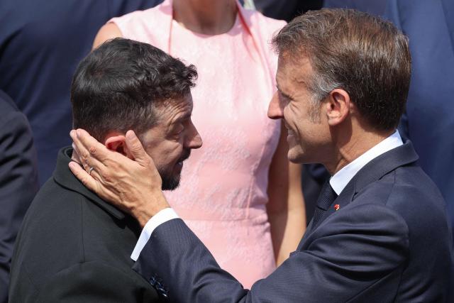 France's President Emmanuel Macron (R) greets Ukraine's President Volodymyr Zelensky during the annual Bastille Day military parade on the Champs-Elysees Avenue in Paris on July 14, 2026. (Photo by Ludovic MARIN / AFP)