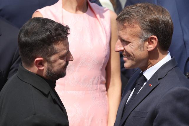 France's President Emmanuel Macron (R) greets Ukraine's President Volodymyr Zelensky during the annual Bastille Day military parade on the Champs-Elysees Avenue in Paris on July 14, 2026. (Photo by Ludovic MARIN / AFP)