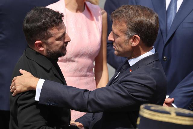 France's President Emmanuel Macron (R) greets Ukraine's President Volodymyr Zelensky during the annual Bastille Day military parade on the Champs-Elysees Avenue in Paris on July 14, 2026. (Photo by Ludovic MARIN / AFP)