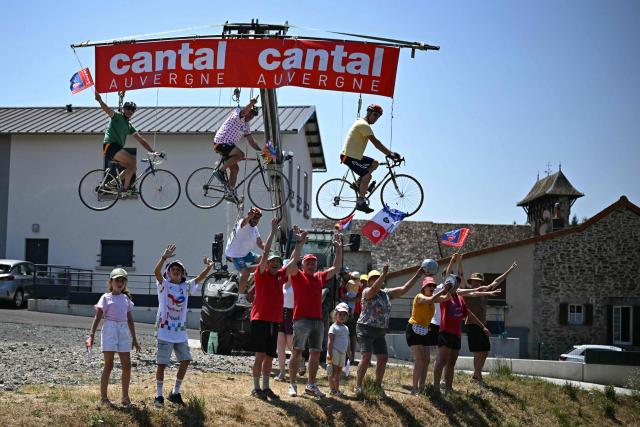 Spectators ride bicycles hanging from a telehandler along the race route at the start of the 10th stage of the 113th edition of the Tour de France cycling race, 166,6 km between Aurillac and Le Lioran in the Massif Central, on July 14, 2026. (Photo by Loic VENANCE / AFP)