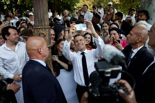 French President Emmanuel Macron takes a selfie with spectators at the end of the annual Bastille Day military parade on the Champs-Elysees Avenue in Paris on July 14, 2026. (Photo by Benoit Tessier / POOL / AFP)