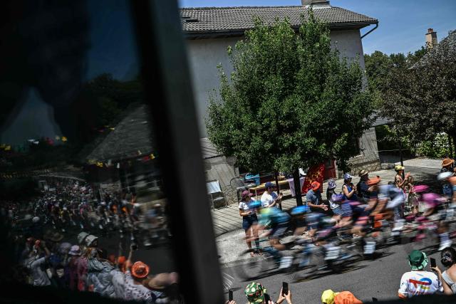 The pack of riders (peloton) are reflected in a window as they cycle during the 10th stage of the 113th edition of the Tour de France cycling race, 166,6 km between Aurillac and Le Lioran in the Massif Central, on July 14, 2026. (Photo by Loic VENANCE / AFP)