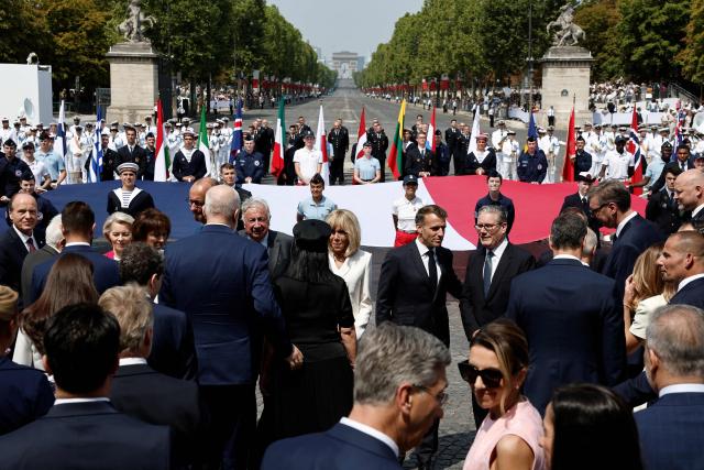 France's President Emmanuel Macron (C-R), his wife Brigitte Macron (C) and Heads of State and Government of the Coalition of the Willing leave at the end of the annual Bastille Day military parade on the Place de la Concorde in Paris, France, July 14, 2026. (Photo by Benoit Tessier / POOL / AFP)