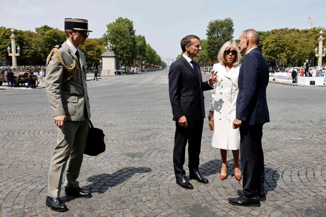 French President Emmanuel Macron (C) and his wife Brigitte Macron (2R) leave after the annual Bastille Day military parade on the Champs-Elysees Avenue in Paris on July 14, 2026. (Photo by Benoit Tessier / POOL / AFP)