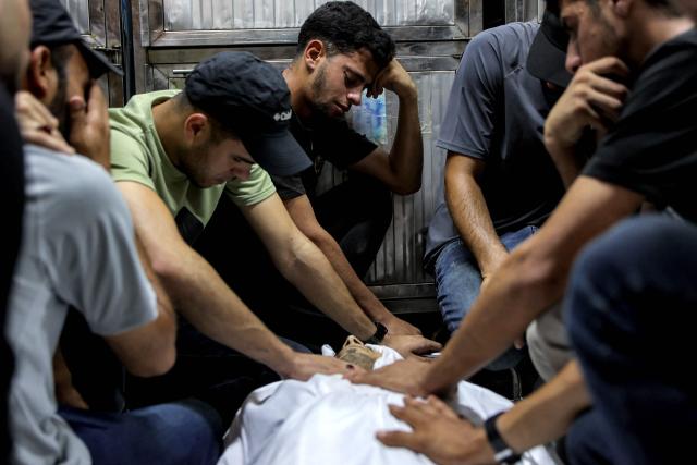 EDITORS NOTE: Graphic content / Mourners bid farewell to the body of one of several victims who were killed after a police station was was hit by Israeli bombardment in the Jabalia camp for Palestinian refugees in the northern Gaza Strip, as they gather ahead of the funeral at a morgue at al-Shifa Hosital in Gaza City on July 14, 2026. Gaza's civil defence agency and the hospital said that the Israeli airstrike on the police station in northern Gaza killed eight people on July 14, including a woman officer. In a statement condemning the strike, Palestinian Islamist movement Hamas, which controls Gaza's police force, said that the police station chief was among those killed. (Photo by Omar AL-QATTAA / AFP)