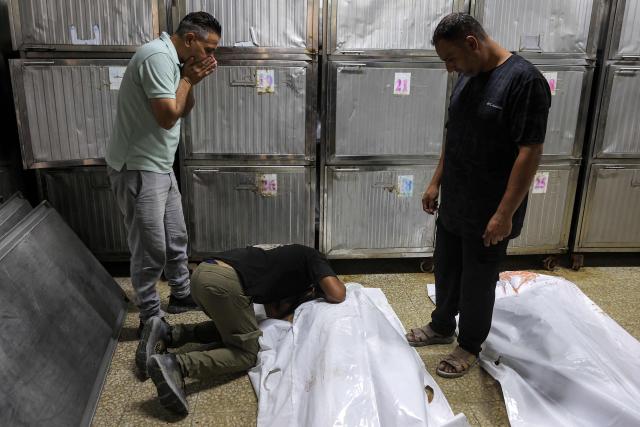 EDITORS NOTE: Graphic content / Men grieve by the body of one of several victims who were killed after a police station was was hit by Israeli bombardment in the Jabalia camp for Palestinian refugees in the northern Gaza Strip, ahead of the funeral at a morgue at al-Shifa Hosital in Gaza City on July 14, 2026. Gaza's civil defence agency and the hospital said that the Israeli airstrike on the police station in northern Gaza killed eight people on July 14, including a woman officer. In a statement condemning the strike, Palestinian Islamist movement Hamas, which controls Gaza's police force, said that the police station chief was among those killed. (Photo by Omar AL-QATTAA / AFP)