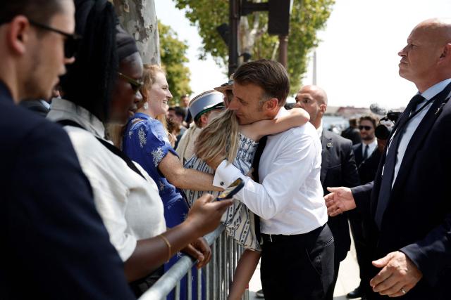 France's President Emmanuel Macron hugs a child as he greets members of the public after the annual Bastille Day military parade on the Place de la Concorde in Paris, France, July 14, 2026. (Photo by Benoit Tessier / POOL / AFP)
