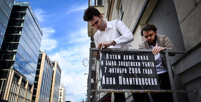 Activists of the Russian liberal Yabloko political party, including Ivan Dorofeyev (dressed in white shirt), install an improvised memorial plaque at the entrance to the house of slain investigative journalist Anna Politkovskaya in Moscow on July 14, 2026. Novaya Gazeta newspaper reporter Anna Politkovskaya, who reported on political and social events in Russia, in particular the Chechen War, was found murdered in the elevator of her apartment block in Moscow on October 7, 2006, on Russian President Vladimir Putin's birthday. Politkovskaya was one of Putin's critics and conducted investigations about links between the Chechen authorities and violent organised crime. (Photo by Alexander NEMENOV / AFP)
