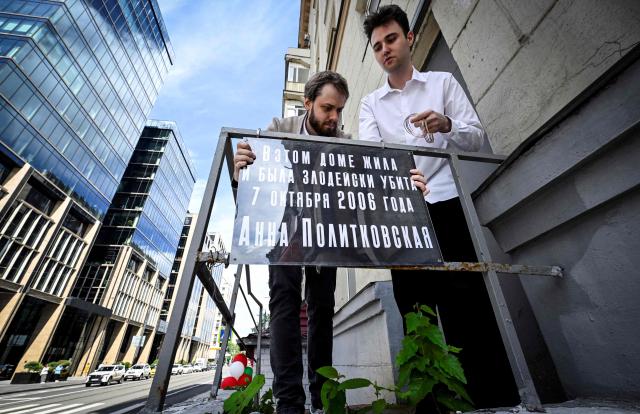 Activists of the Russian liberal Yabloko political party, including Ivan Dorofeyev (dressed in white shirt), install an improvised memorial plaque at the entrance to the house of slain investigative journalist Anna Politkovskaya in Moscow on July 14, 2026. Novaya Gazeta newspaper reporter Anna Politkovskaya, who reported on political and social events in Russia, in particular the Chechen War, was found murdered in the elevator of her apartment block in Moscow on October 7, 2006, on Russian President Vladimir Putin's birthday. Politkovskaya was one of Putin's critics and conducted investigations about links between the Chechen authorities and violent organised crime. (Photo by Alexander NEMENOV / AFP)