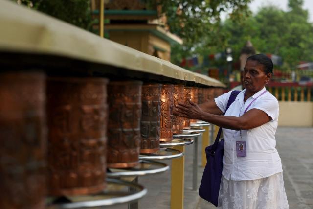 A tourist spins a prayer wheel at the Bodhi Mandap inside the Mulagandha Kuti Vihar, a Buddhist monastery and temple, at Sarnath on the outskirts of Varanasi on July 14, 2026. (Photo by Niharika KULKARNI / AFP)