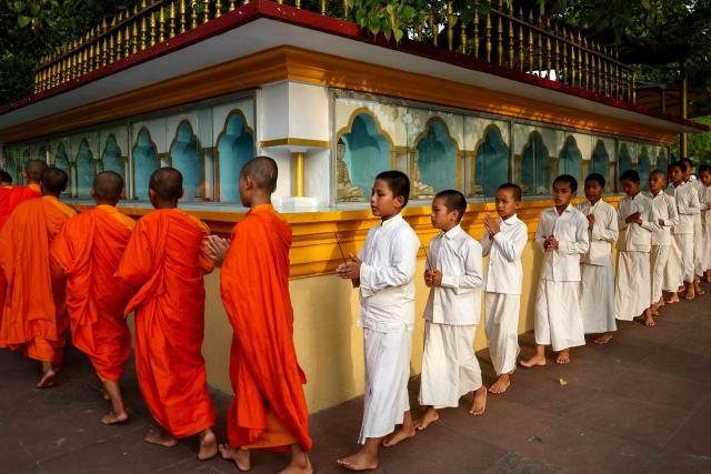 Young Buddhist monks pray around statues of Buddha at the Bodhi Mandap inside the Mulagandha Kuti Vihar, a Buddhist monastery and temple, at Sarnath on the outskirts of Varanasi on July 14, 2026. (Photo by Niharika KULKARNI / AFP)