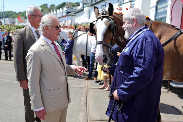 Britain's King Charles III (L) speaks with Peter Cannon (R) and meets a working horse from the Douglas Horse Tramway, along the promenade in Douglas on the Isle of Man, an island in the Irish Sea off of the west coast England, on July 14, 2026, to celebrate 150 years of the tramway. (Photo by Chris Jackson / POOL / AFP)
