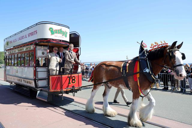 Britain's King Charles III (L) rides on one of the horse trams along the promenade in Douglas on the Isle of Man, an island in the Irish Sea off of the west coast England, on July 14, 2026, to celebrate 150 years of the Douglas Horse Tramway. (Photo by Chris Jackson / POOL / AFP)