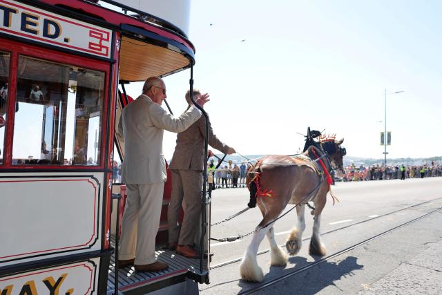 Britain's King Charles III (L) rides on one of the horse trams along the promenade in Douglas on the Isle of Man, an island in the Irish Sea off of the west coast England, on July 14, 2026, to celebrate 150 years of the Douglas Horse Tramway. (Photo by Chris Jackson / POOL / AFP)