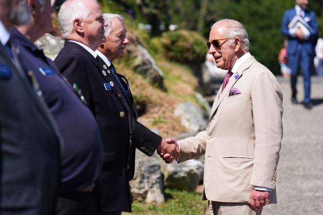 Britain's King Charles III (R) meets veterans at the charity 'Heroes On The Water Isle of Man', in Port Soderick on the Isle of Man, an island in the Irish Sea off of the west coast England, on July 14, 2026. 'Heroes On The Water Isle of Man' is a charity that supports military veterans, emergency service personnel and other uniformed public servants through kayak angling and outdoor activities. (Photo by Aaron Chown / POOL / AFP)