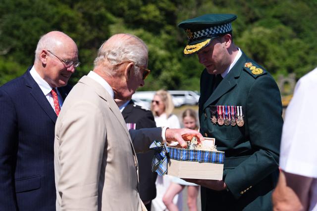 Britain's King Charles III (2nd L) is gifted a bell from a retired ambulance, during a visit to the charity 'Heroes On The Water Isle of Man', in Port Soderick on the Isle of Man, an island in the Irish Sea off of the west coast England, on July 14, 2026. 'Heroes On The Water Isle of Man' is a charity that supports military veterans, emergency service personnel and other uniformed public servants through kayak angling and outdoor activities. (Photo by Aaron Chown / POOL / AFP)
