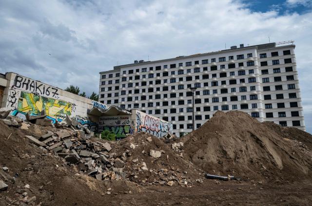 A newly-built residential complex is seen behind the rubble of a construction site featuring an old East German swimming pool facility, in Berlin on July 14, 2026. (Photo by John MACDOUGALL / AFP)