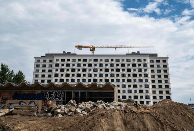 A newly-built residential complex is seen behind the rubble of a construction site featuring an old East German swimming pool facility, in Berlin on July 14, 2026. (Photo by John MACDOUGALL / AFP)