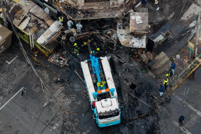 Aerial view after a van collided with a Metropolitan Transport Network (RED) bus in the Franklin neighborhood, Santiago, Chile, on July 14, 2026. Five people died in an accident between a van and a bus which caused a fire that engulfed the public transport vehicle and commercial premises. (Photo by Javier TORRES / AFP)