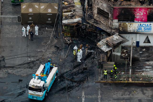 Aerial view after a van collided with a Metropolitan Transport Network (RED) bus in the Franklin neighborhood, Santiago, Chile, on July 14, 2026. Five people died in an accident between a van and a bus which caused a fire that engulfed the public transport vehicle and commercial premises. (Photo by Javier TORRES / AFP)