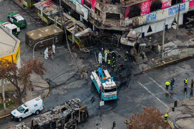 Aerial view after a van collided with a Metropolitan Transport Network (RED) bus in the Franklin neighborhood, Santiago, Chile, on July 14, 2026. Five people died in an accident between a van and a bus which caused a fire that engulfed the public transport vehicle and commercial premises. (Photo by Javier TORRES / AFP)