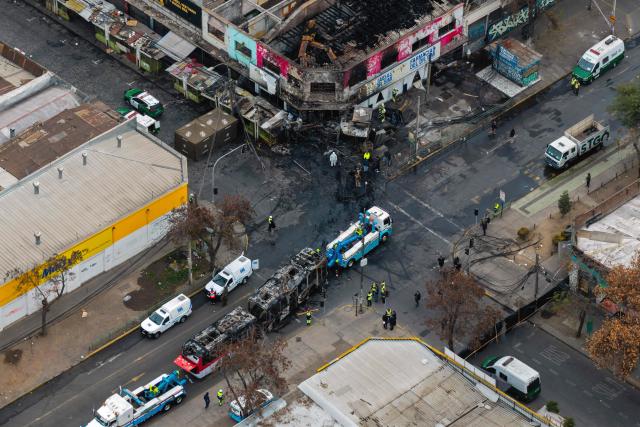 Aerial view after a van collided with a Metropolitan Transport Network (RED) bus in the Franklin neighborhood, Santiago, Chile, on July 14, 2026. Five people died in an accident between a van and a bus which caused a fire that engulfed the public transport vehicle and commercial premises. (Photo by Javier TORRES / AFP)