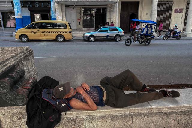 A man sleeps on a bench at the Paseo del Parado during a widespread blackout in Havana on July 14, 2026. Cuba's power grid failed for the third time in less than 10 days, sparking another nationwide blackout, the national electricity company said on July 14, 2026. (Photo by YAMIL LAGE / AFP)