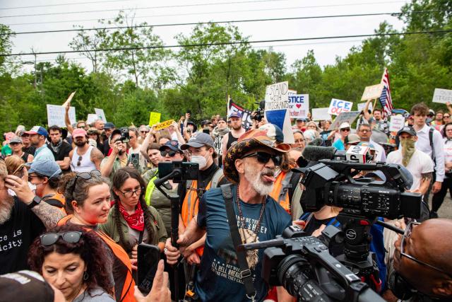 A man armed with a gun and a knife confronts demonstrators holding a protest outside of the Immigration and Customs Enforcement (ICE) field office in Scarborough, Maine, on July 14, 2026. A US immigration officer on July 13, fatally shot a man identified by rights groups as a 26-year-old Colombian, an incident likely to fuel criticism of President Donald Trump's deportation drive. The shooting happened in Biddeford, a town of 22,000 people in the northern state of Maine, and comes a week after an Immigration and Customs Enforcement (ICE) agent shot dead a Mexican man in Texas. (Photo by JOSEPH PREZIOSO / AFP)