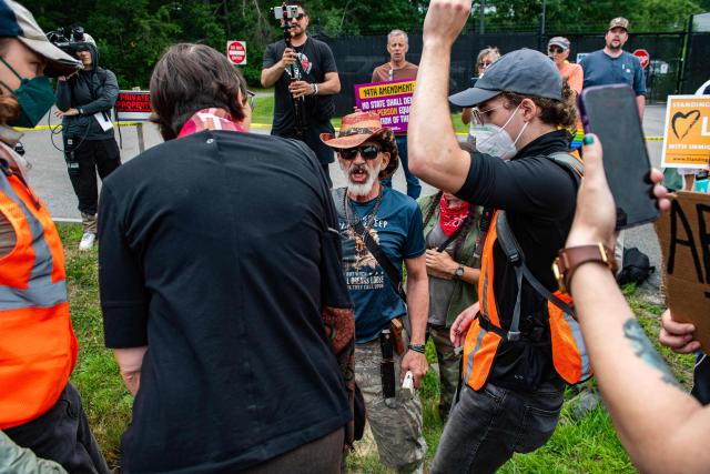 A man armed with a gun and a knife confronts demonstrators holding a protest outside of the Immigration and Customs Enforcement (ICE) field office in Scarborough, Maine, on July 14, 2026. A US immigration officer on July 13, fatally shot a man identified by rights groups as a 26-year-old Colombian, an incident likely to fuel criticism of President Donald Trump's deportation drive. The shooting happened in Biddeford, a town of 22,000 people in the northern state of Maine, and comes a week after an Immigration and Customs Enforcement (ICE) agent shot dead a Mexican man in Texas. (Photo by JOSEPH PREZIOSO / AFP)