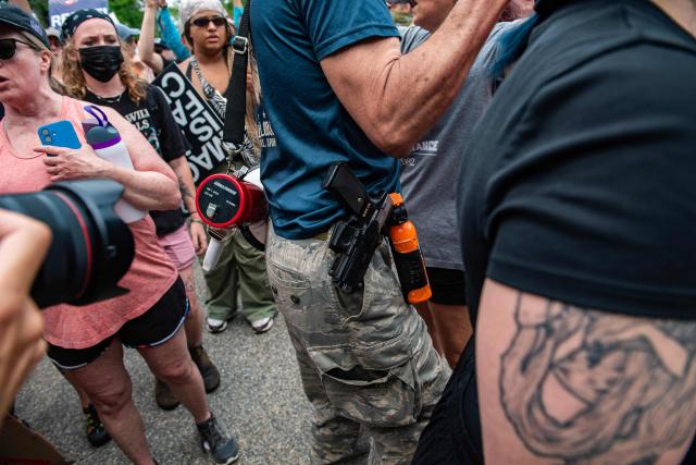 A man armed with a gun and a knife confronts demonstrators holding a protest outside of the Immigration and Customs Enforcement (ICE) field office in Scarborough, Maine, on July 14, 2026. A US immigration officer on July 13, fatally shot a man identified by rights groups as a 26-year-old Colombian, an incident likely to fuel criticism of President Donald Trump's deportation drive. The shooting happened in Biddeford, a town of 22,000 people in the northern state of Maine, and comes a week after an Immigration and Customs Enforcement (ICE) agent shot dead a Mexican man in Texas. (Photo by JOSEPH PREZIOSO / AFP)