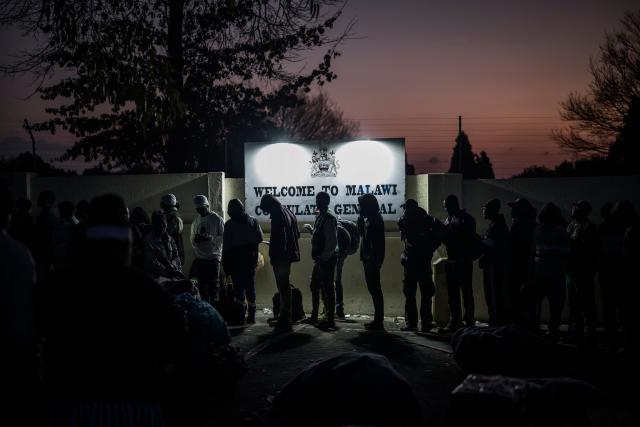 TOPSHOT - Malawian migrants line up in front of their Consulate in Johannesburg, on July 14, 2026 ahead of their repatriation towards Malawi. Several thousands more foreign nationals clamoured to leave South Africa on July 3, after a push that has already seen around 35,000 go home. The exodus began weeks ago as fringe groups began demanding all illegal migrants leave by June 30, in a campaign that saw violent protests and clashes. (Photo by MARCO LONGARI / AFP)