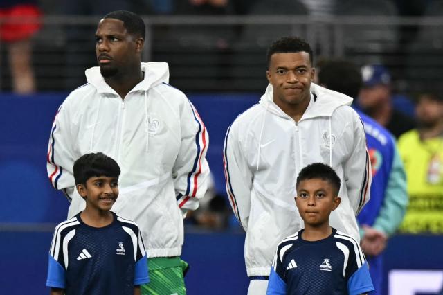 France's forward #10 Kylian Mbappe (R) and France's goalkeeper #16 Mike Maignan stand for the national anthems ahead of the 2026 World Cup football tournament semi-final match between France and Spain at the Dallas Stadium in Arlington on July 14, 2026.  (Photo by Paul ELLIS / AFP)