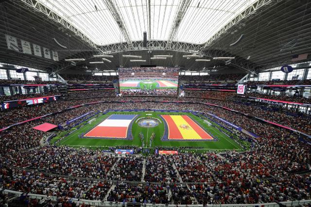 Frances' players (L) and Spain's players (R) stand for the national anthems ahead of the 2026 World Cup football tournament semi-final match between France and Spain at the Dallas Stadium in Arlington on July 14, 2026.  (Photo by Aric Becker / AFP)