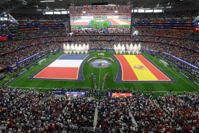 Pyrotechnics erupt as Frances' players (L) and Spain's players (R) stand ahead of the 2026 World Cup football tournament semi-final match between France and Spain at the Dallas Stadium in Arlington on July 14, 2026.  (Photo by Aric Becker / AFP)