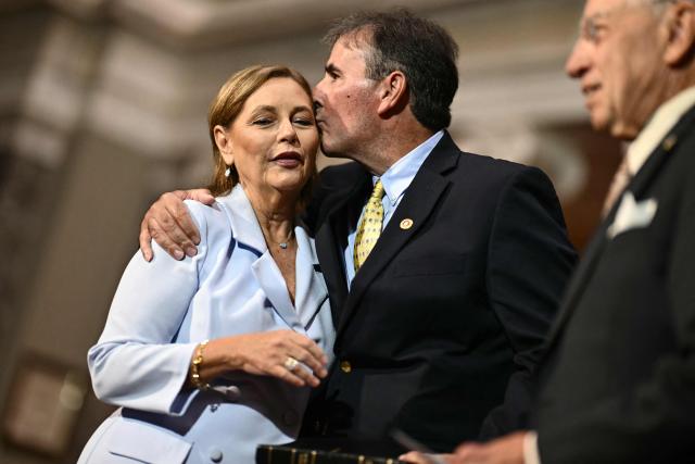 Darline Graham Nordone (L), sister of Lindsey Graham, is embraced by her husband Larry Nordone after being ceremonially sworn in as a US Senator by Senator Charles Grassley (R), Republican from Iowa, in the Old Senate Chamber at the US Capitol in Washington, DC, on July 14, 2026. South Carolina Governor Henry McMaster on July 13 appointed the late Republican senator Lindsey Graham's younger sister to complete his term, hours after President Donald Trump publicly urged him to choose her. Darline Graham Nordone will serve in the US Senate until Graham's term expires in January, following his unexpected death at the weekend at the age of 71. (Photo by Kent NISHIMURA / AFP)
