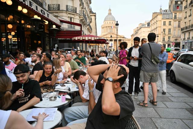 Supporters of France's national football team react after Spain scored a goal from the penalty spot during the 2026 FIFA World Cup semifinal between France and Spain, as they watch the match at a café near the Panthéon (background) in Paris on July 14, 2026. (Photo by Martin LELIEVRE / AFP)