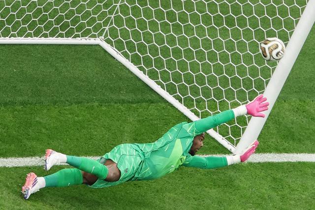 France's goalkeeper #16 Mike Maignan dives for the ball unsuccessfully as he concedes Spain's first goal from the penalty spot during the 2026 World Cup football tournament semi-final match between France and Spain at the Dallas Stadium in Arlington on July 14, 2026.  (Photo by Aric Becker / AFP)