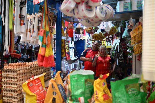 Vendors wear Spanish national football team jerseys at the Duenas Market as they show their support during the FIFA World Cup semifinals between France and Spain, in Santa Tecla, El Salvador, on July 14, 2026. As the tournament reaches its final stages, many market vendors have openly embraced their favorite teams, decorating stalls and market aisles with flags, jerseys and colors in celebration of the competing nations. (Photo by Marvin RECINOS / AFP)