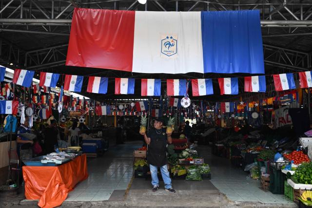 Vendors wait for customers at the Duenas Market where they displayed flags in support of the French national football team during the FIFA World Cup semifinals between France and Spain, in Santa Tecla, El Salvador, on July 14, 2026. As the tournament reaches its final stages, many market vendors have openly embraced their favorite teams, decorating stalls and market aisles with flags, jerseys and colors in celebration of the competing nations. (Photo by Marvin RECINOS / AFP)