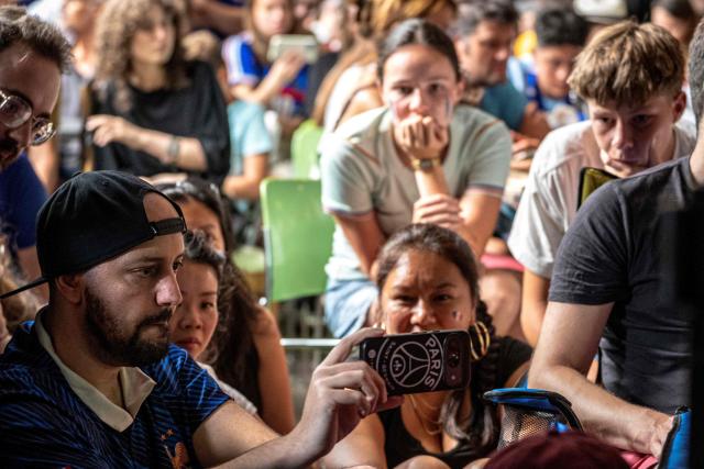 French fans watch the World Cup semi-final game between France and Spain on a phone during minor technical difficulties during an event organized by the French consulate at Robin des Bois in Lafontaine Park in Montreal, Quebec, Canada, on July 14, 2026. (Photo by ANDREJ IVANOV / AFP)
