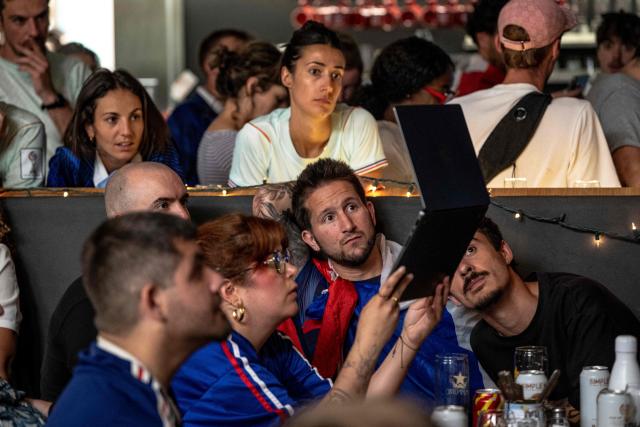 French fans watch the World Cup semi-final game between France and Spain on a computer during minor technical difficulties during an event organized by the French consulate at Robin des Bois in Lafontaine Park in Montreal, Quebec, Canada, on July 14, 2026. (Photo by ANDREJ IVANOV / AFP)