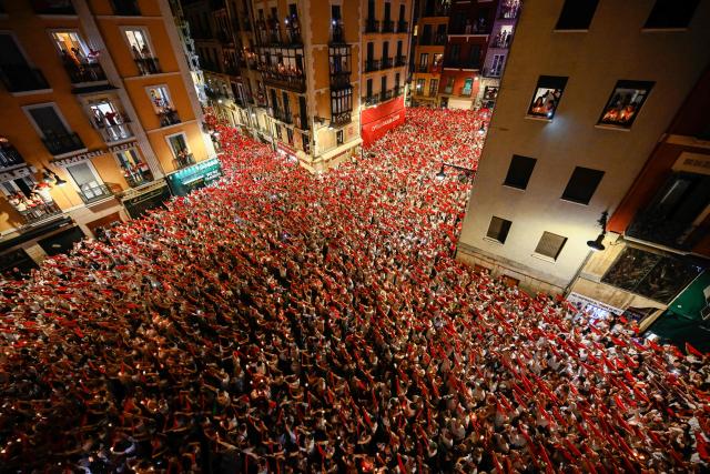 Revellers raise red scarves and candles as they sing the song “Pobre de Mi” marking the end of the San Fermin festival in Pamplona, Spain, early on July 15, 2026. Thousands of people attend the week-long festival and its famous "encierros" or bull runs. Every day at 8:00 a.m., bulls are released through the narrow streets of the old town over an 850-meter course while runners ahead of them try to stay close without falling over or being gored. (Photo by ANDER GILLENEA / AFP)