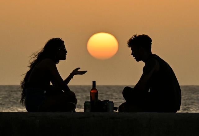 A couple enjoys sunset on the Havana Malecon during a general blackout on July 14, 2026. Cuba's power grid failed for the third time in less than 10 days, sparking another nationwide blackout, the national electricity company said. (Photo by YAMIL LAGE / AFP)